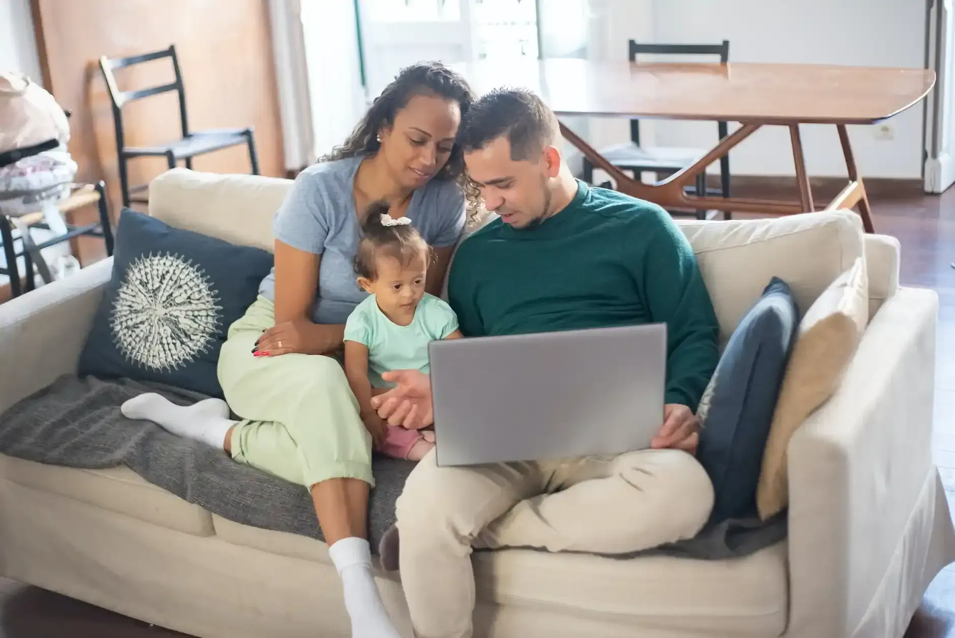 Couple and child on a couch looking at a laptop in a bright living room