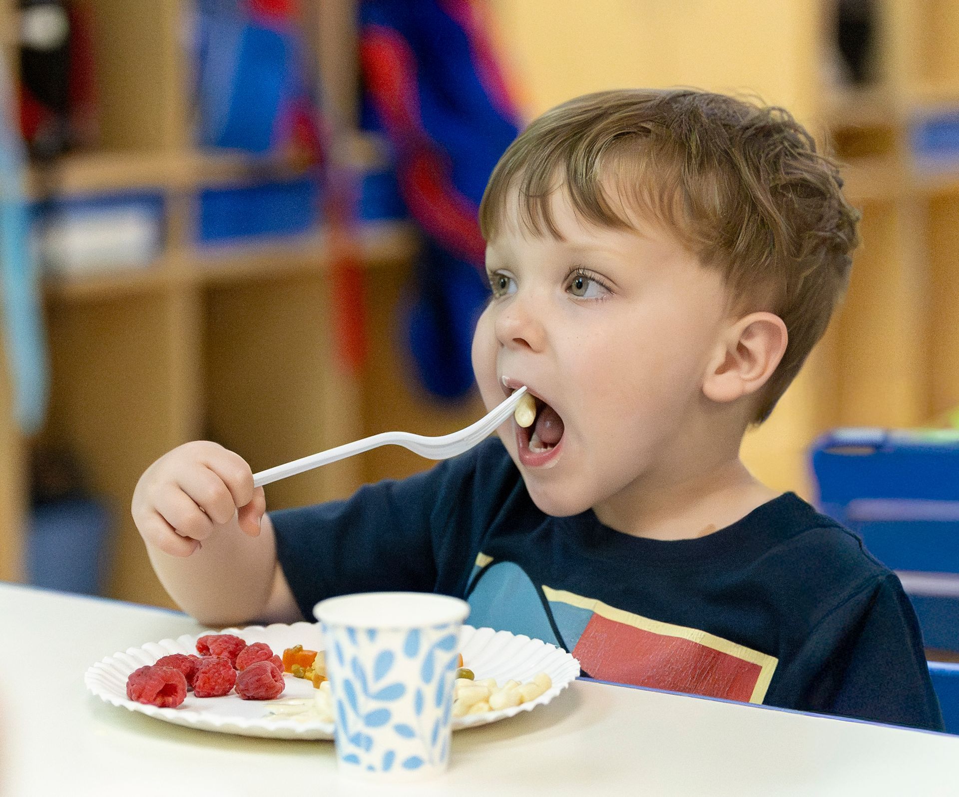 Smiling child in orange shirt building with colorful blocks at a table