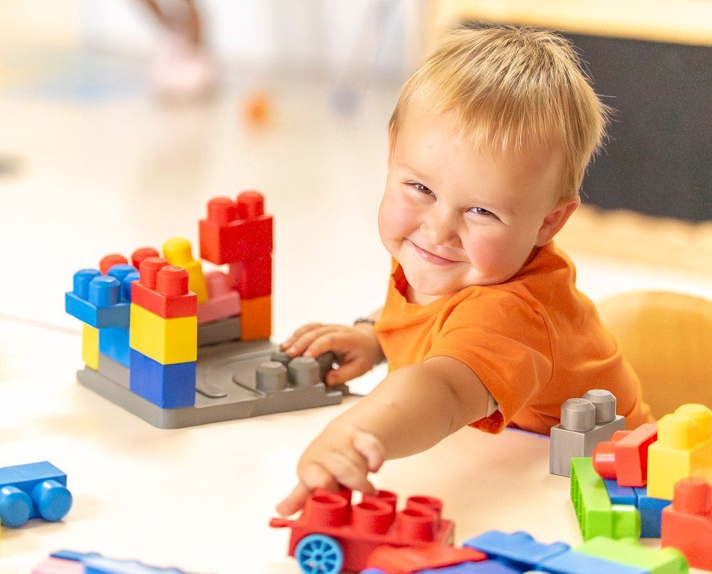 Smiling child playing with colorful building blocks on a table