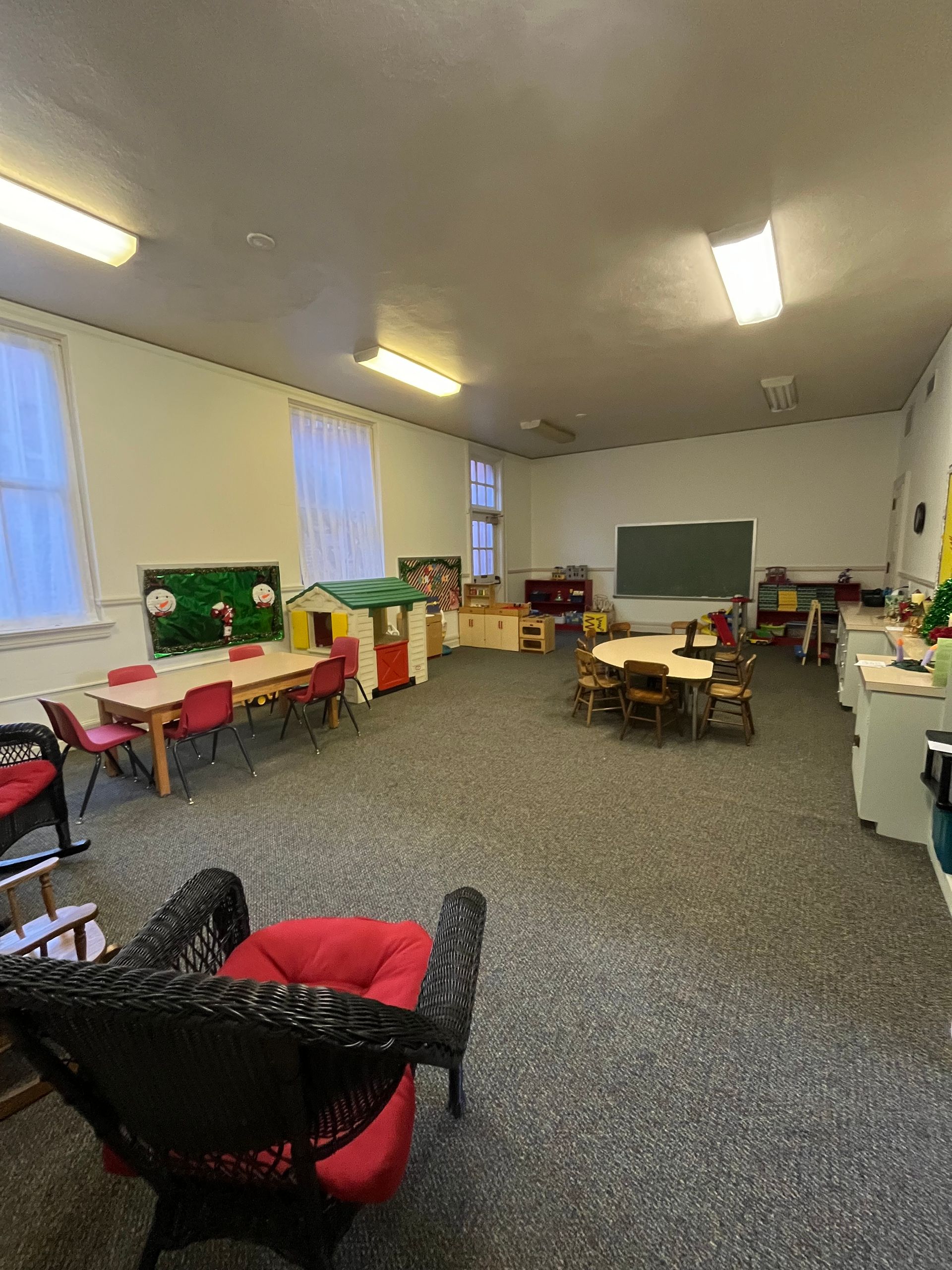 a room with green walls , a desk , chairs and a window .