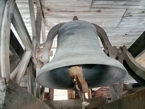 a large bell is sitting on top of a wooden platform in a church .