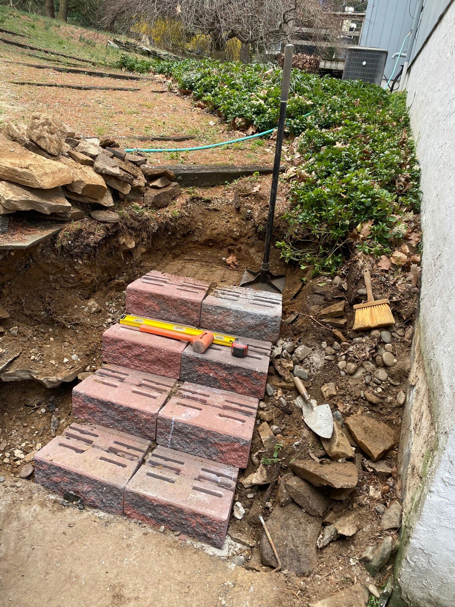 A pile of bricks is sitting on the ground next to a shovel.