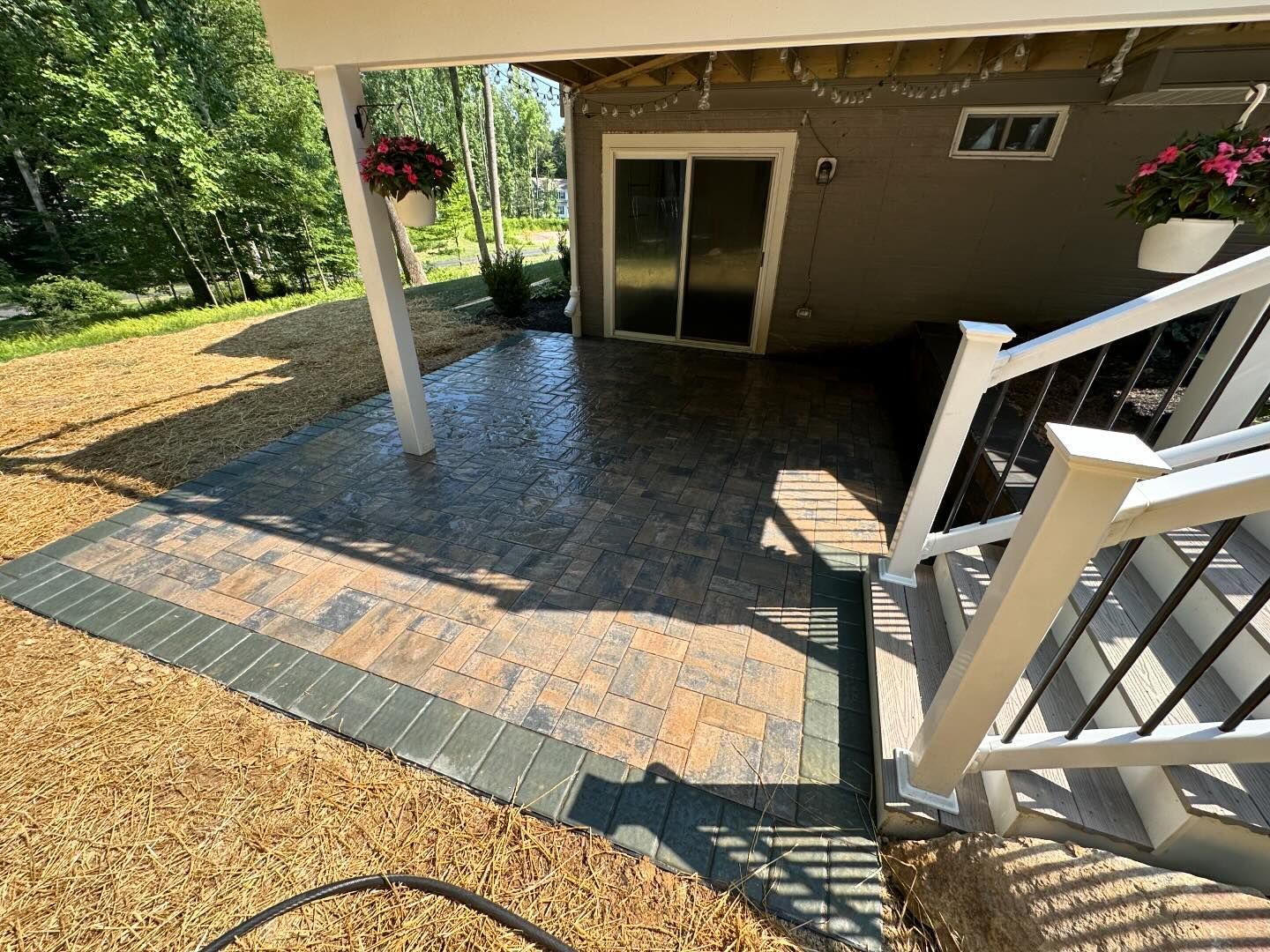 A patio with a sliding glass door and stairs leading up to it.