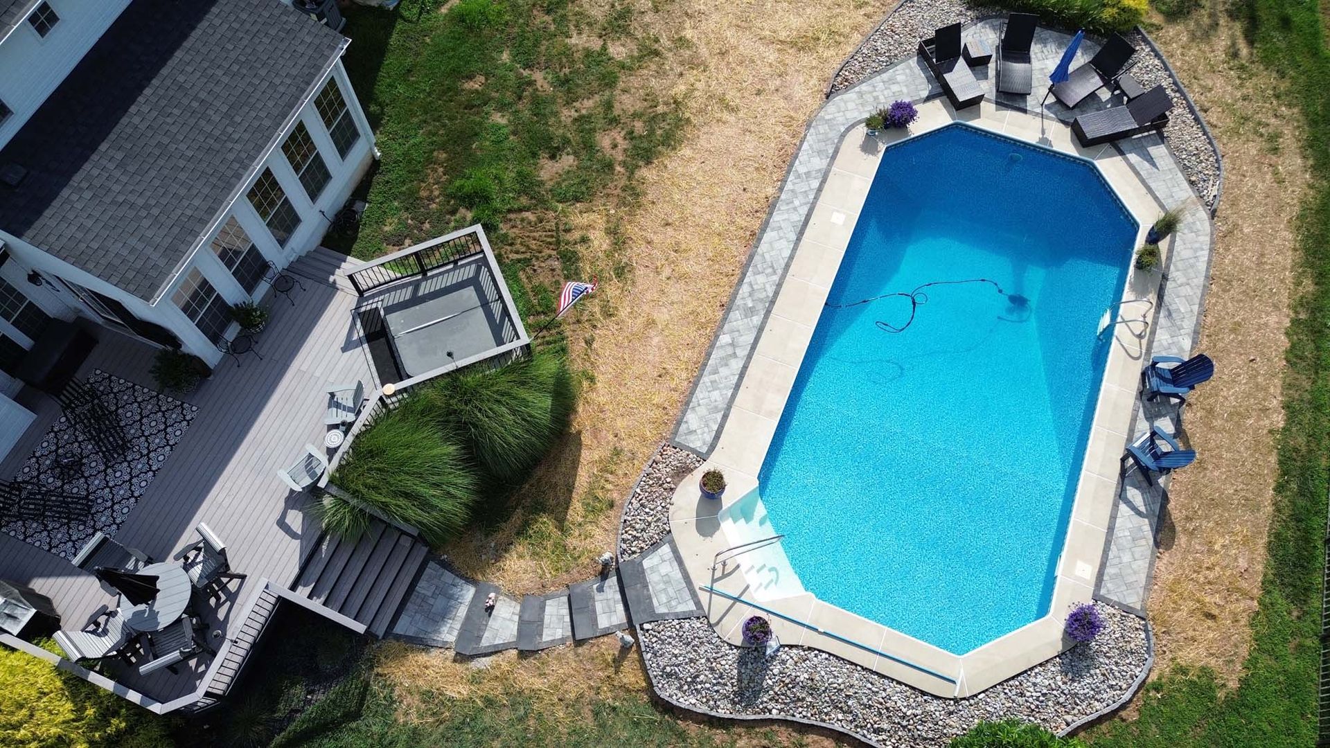 An aerial view of a large swimming pool in the backyard of a house.