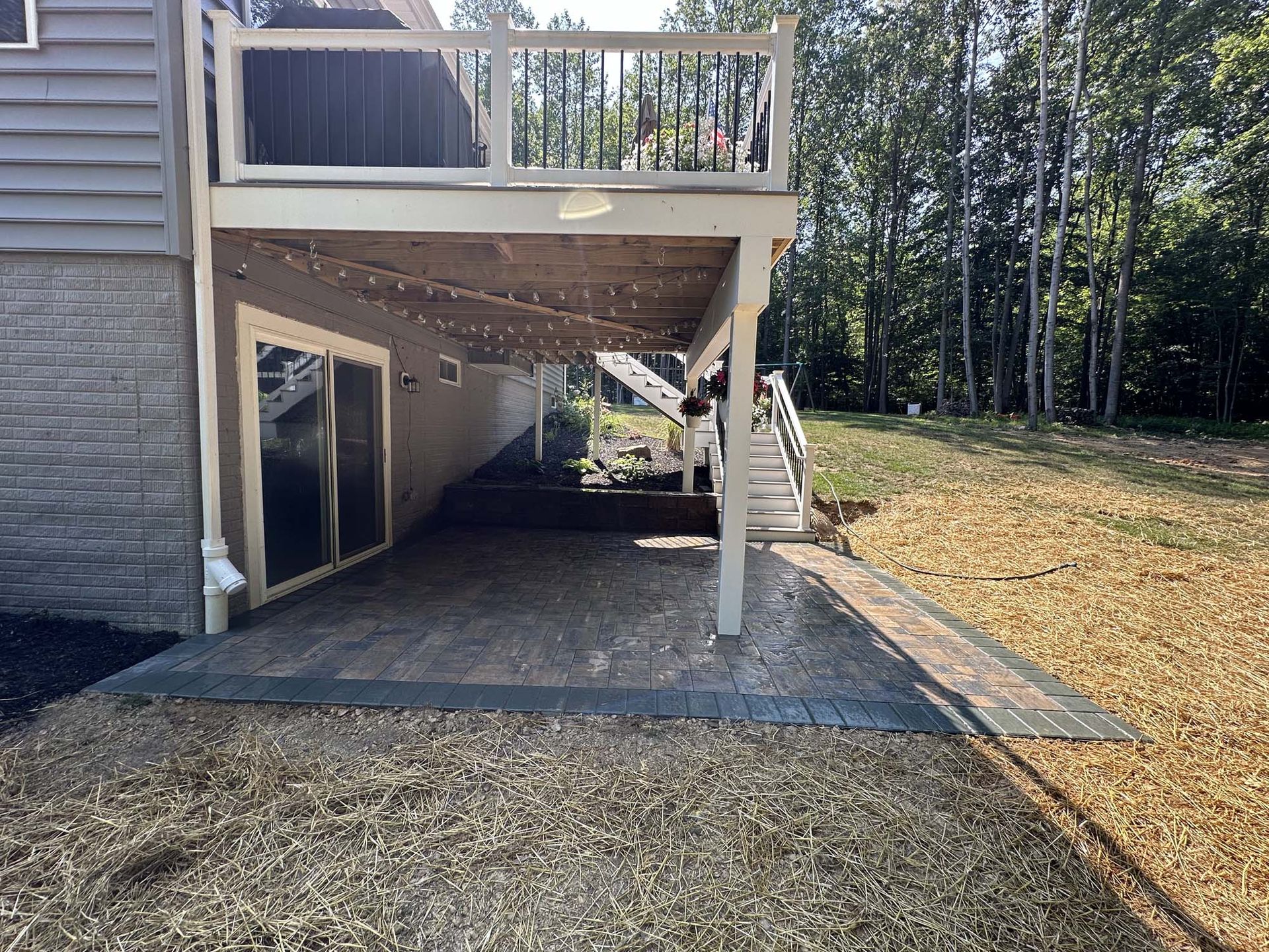 The backyard of a house with a large deck and patio.