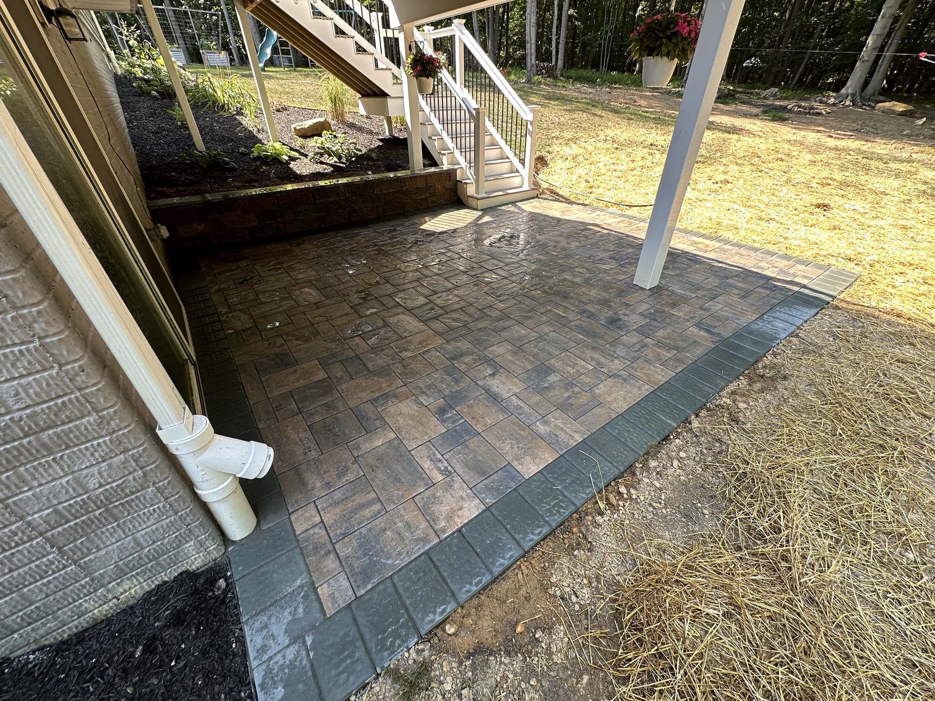 A brick walkway leading to a staircase in a backyard.