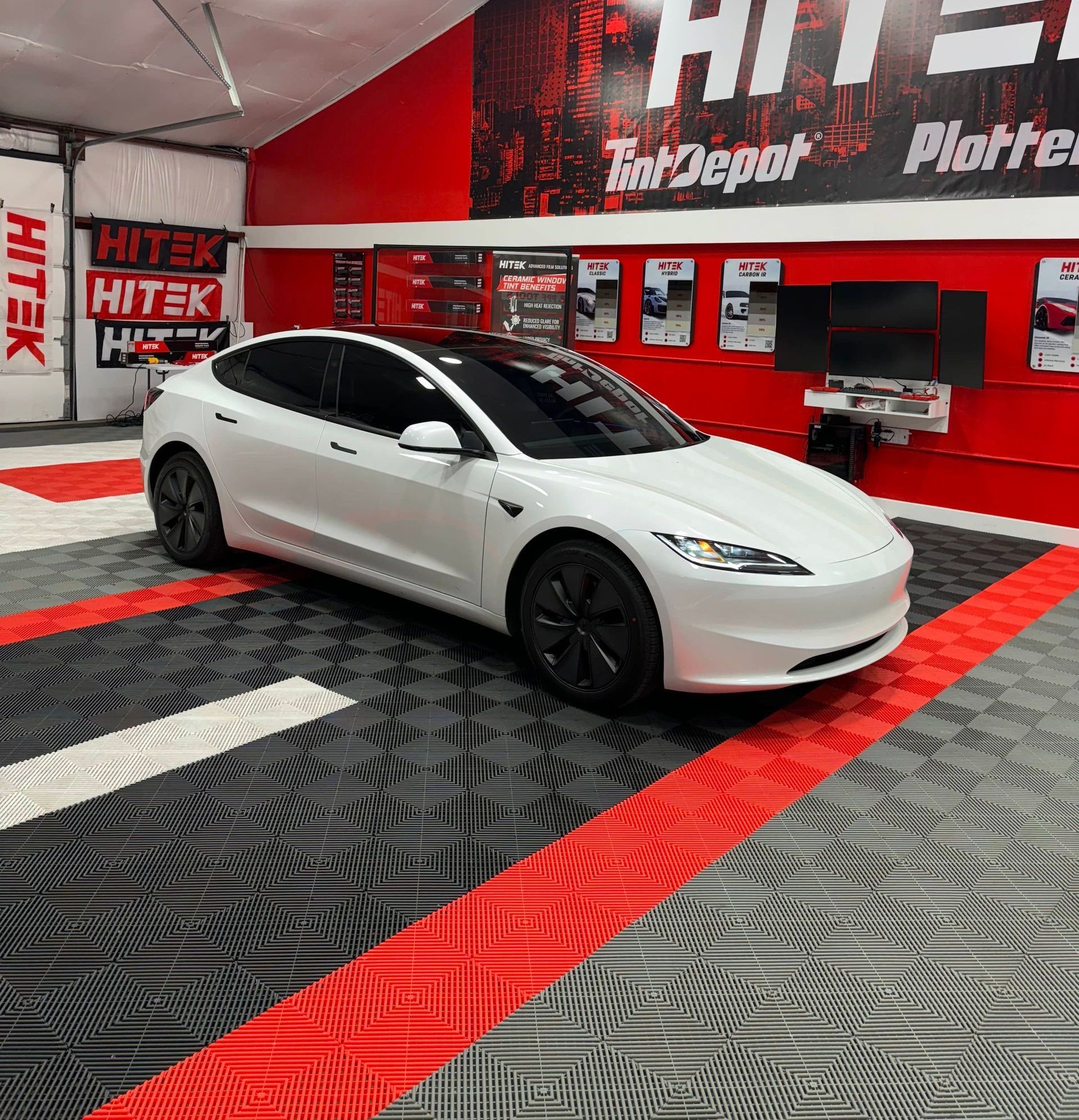 White Tesla with tinted windows inside a tint shop.