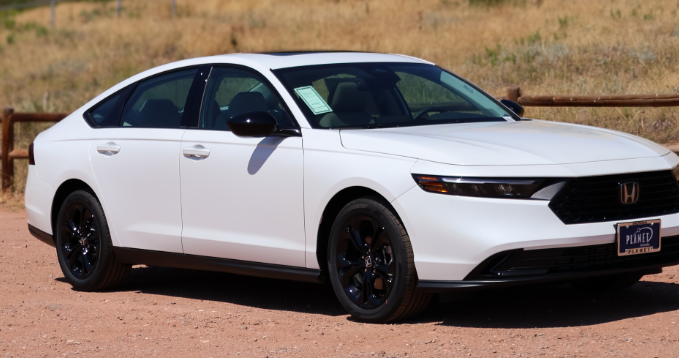 Black sports car in a shop with red and black accents, showcasing tinted windows.
