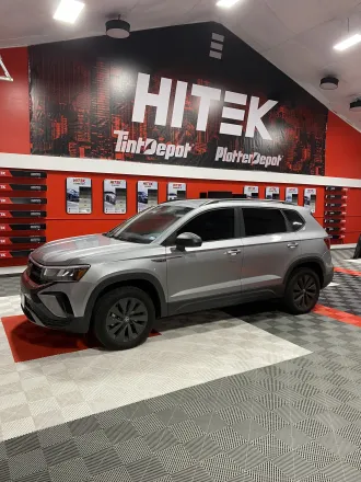 Silver SUV parked in front of a HITEK Tint Depot sign. The interior has red and black accents.