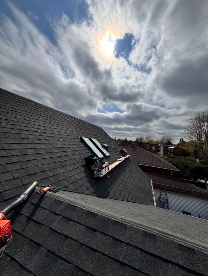 Le soleil brille à travers les nuages ​​au-dessus du toit d'une maison.