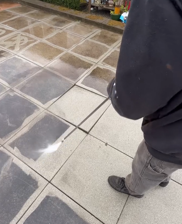 A person standing on a tiled sidewalk with a reflection of a person in the tiles