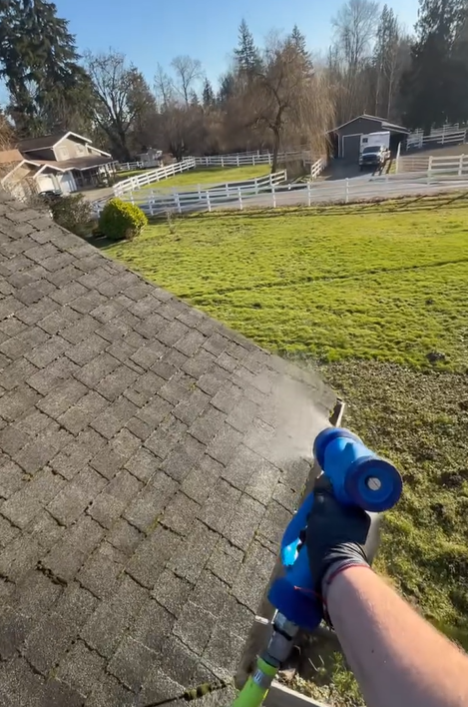 A person is spraying water on a roof with a hose.