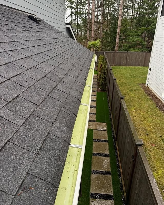 A gutter on the side of a house next to a fence.