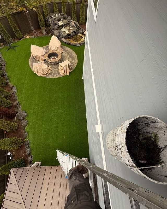 A man is painting the side of a house with a ladder.