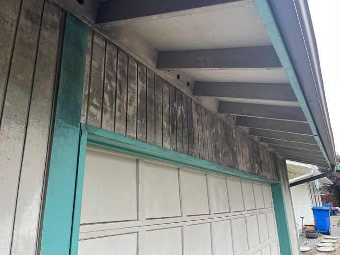 A garage door with a green trim on the side of a house.