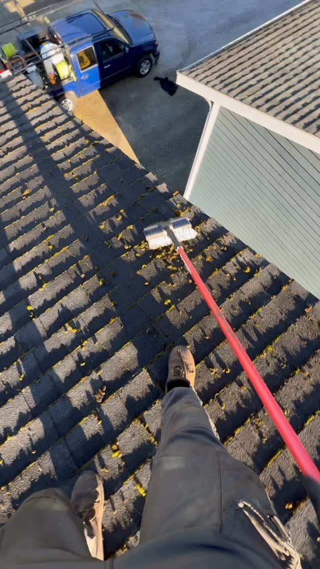 A person is cleaning a roof with a broom.