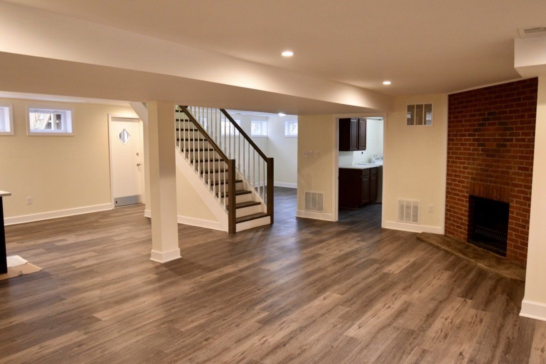 An empty basement with hardwood floors and a fireplace.
