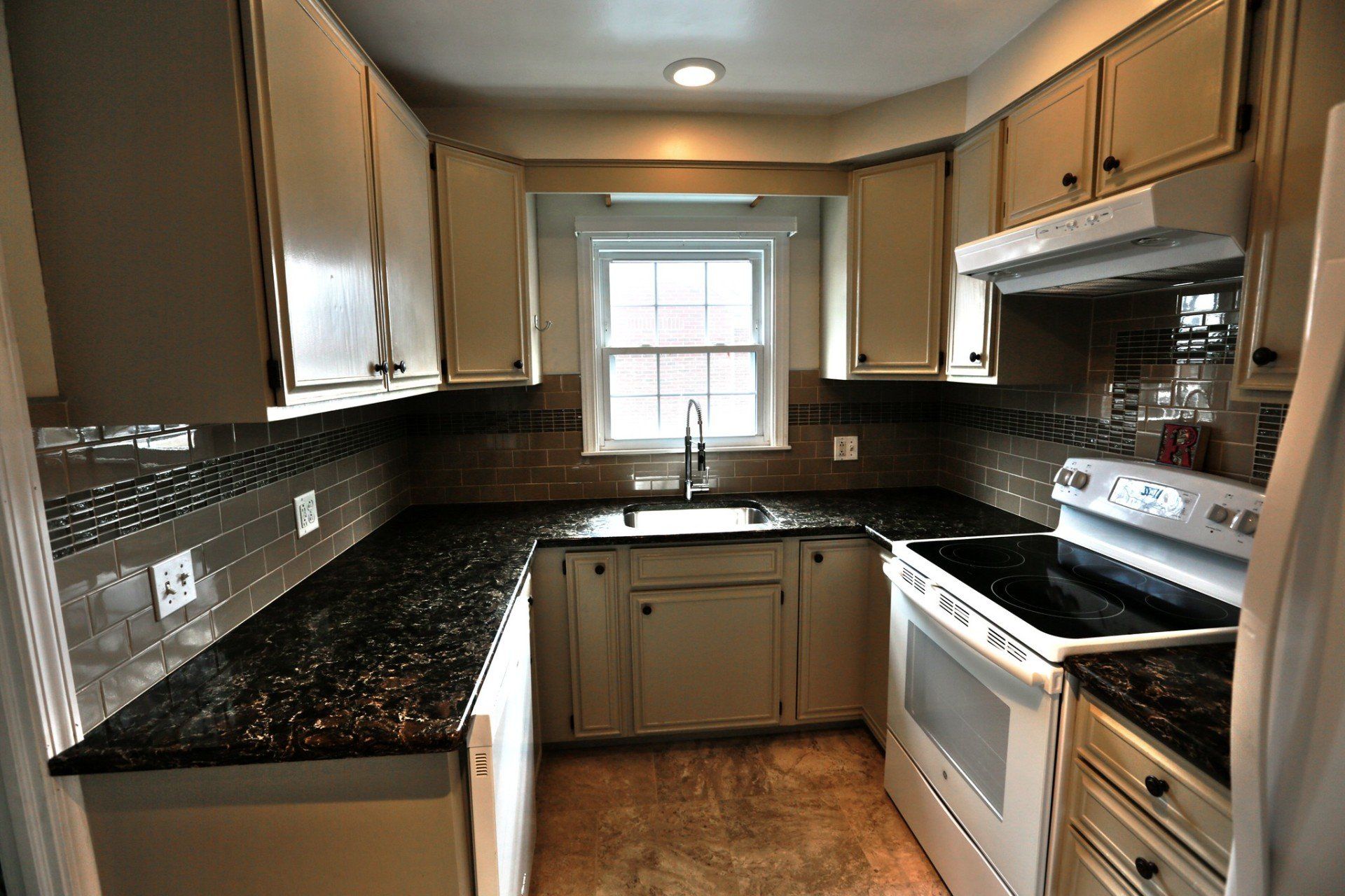 A kitchen with white cabinets and black granite counter tops