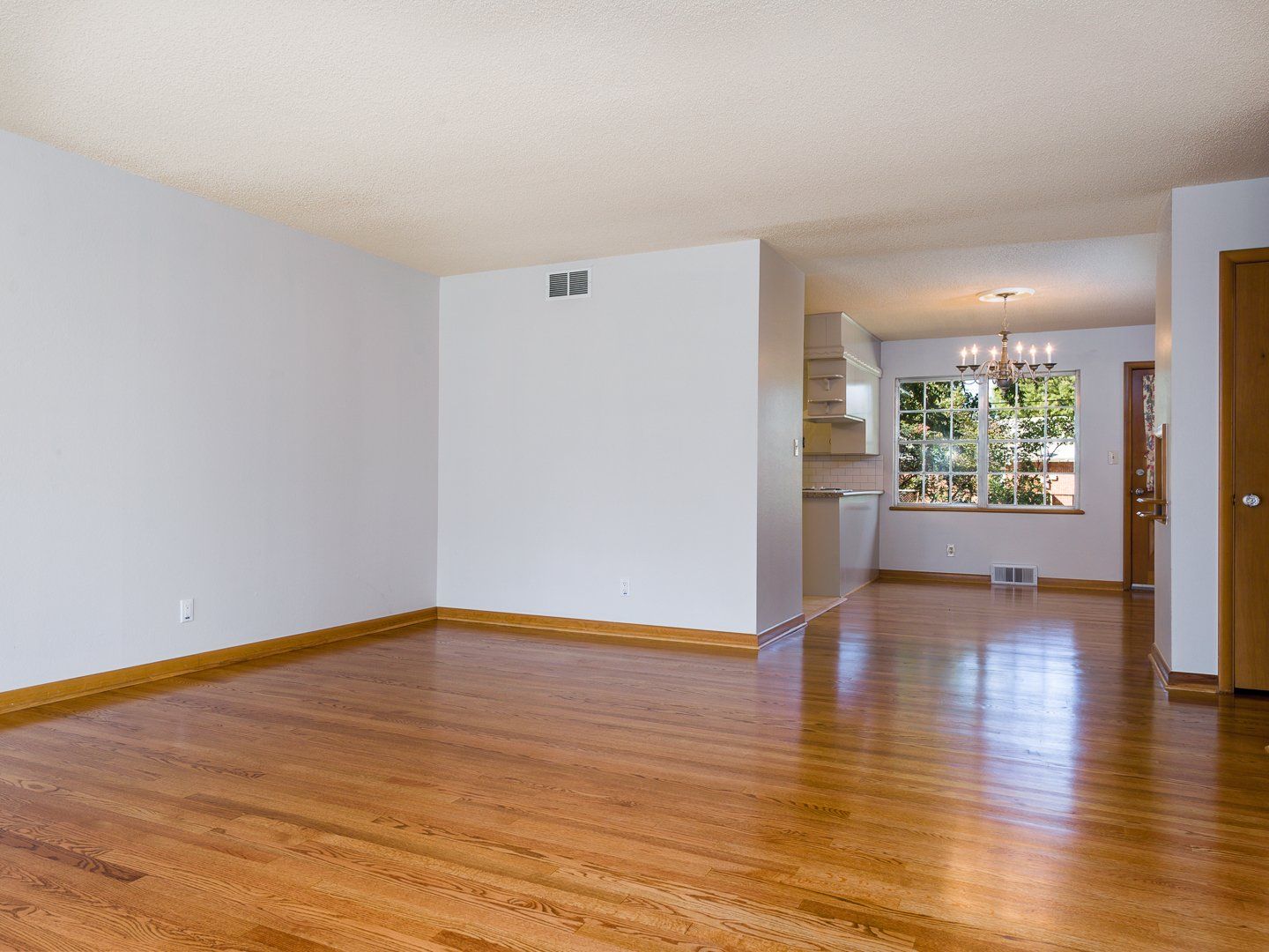 An empty room with hardwood floors and white walls
