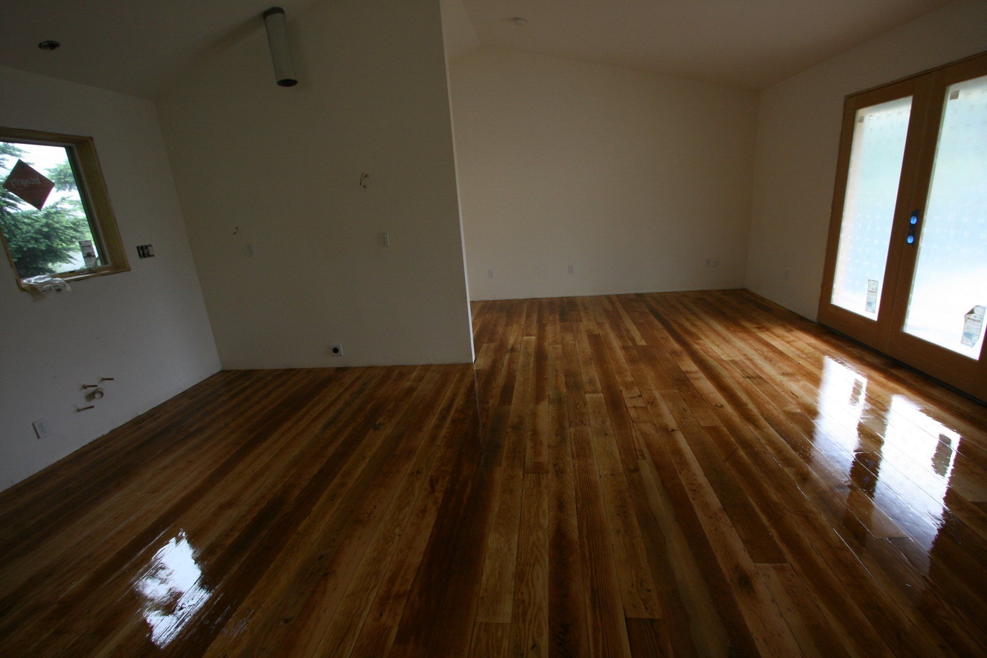 An empty room with a wooden floor and white walls
