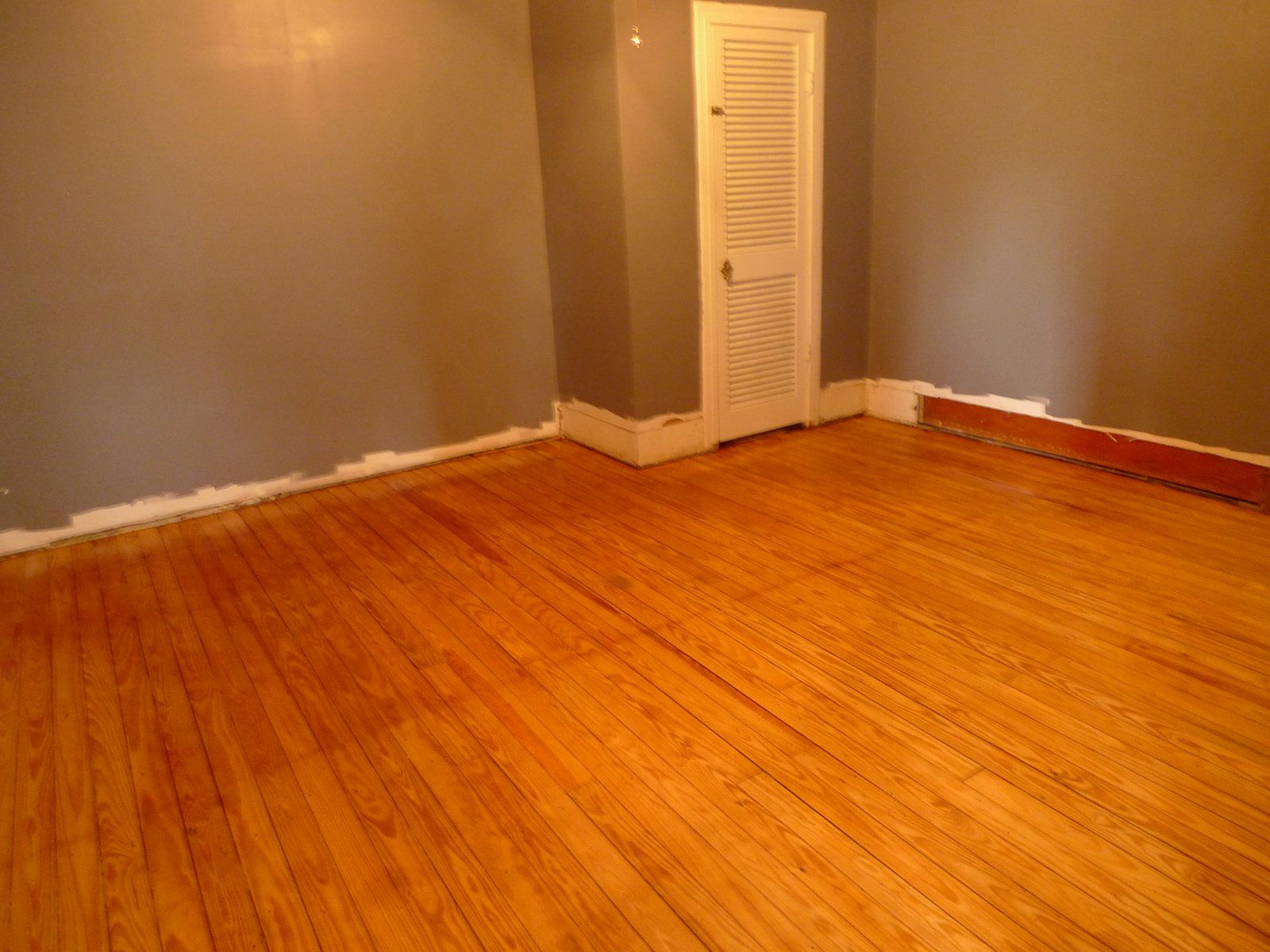 An empty room with hardwood floors and gray walls