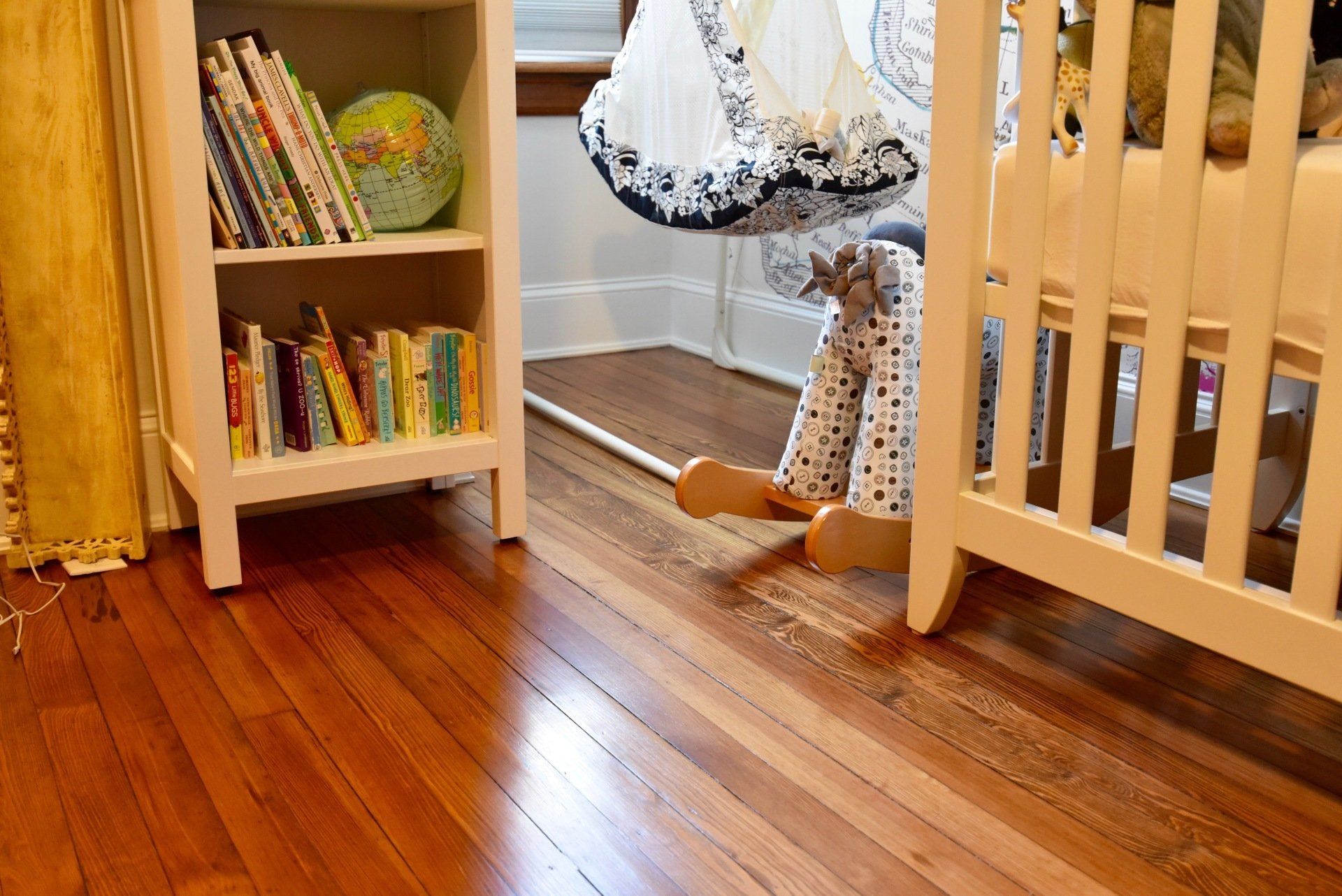 A crib with a rocking horse in front of it