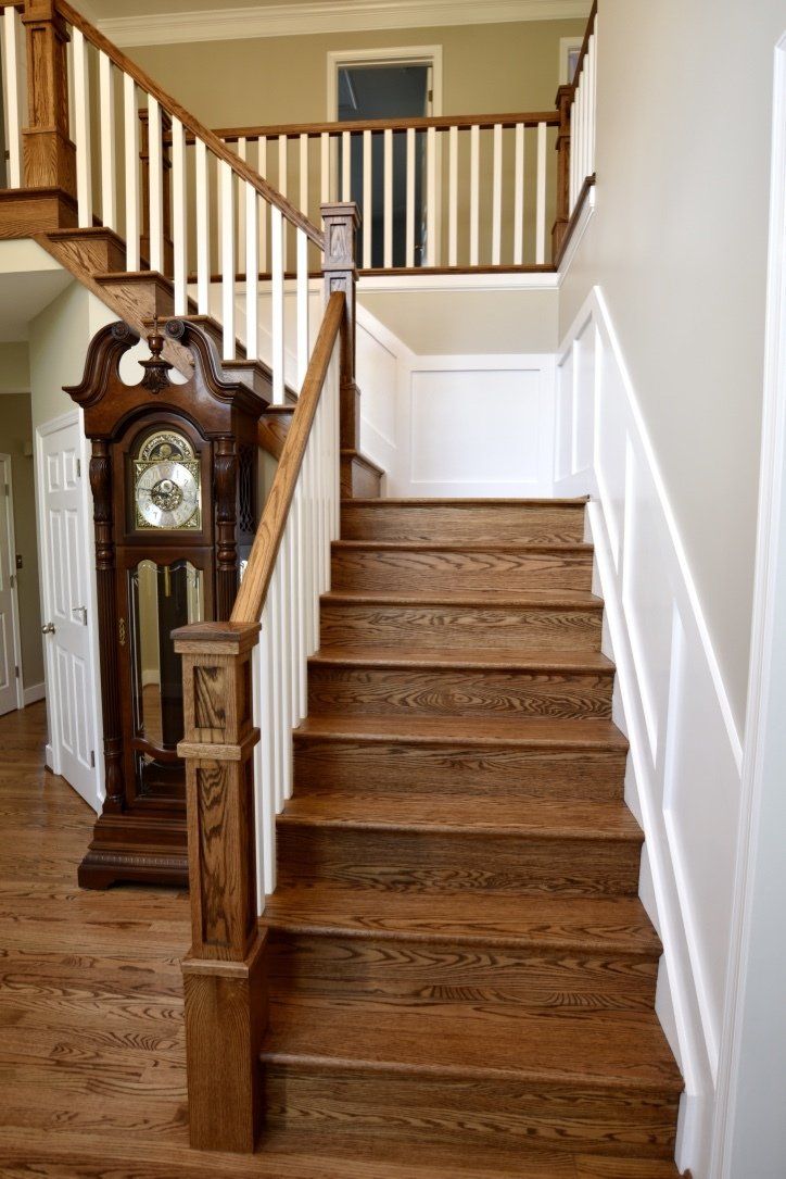 A wooden staircase with a grandfather clock in the background