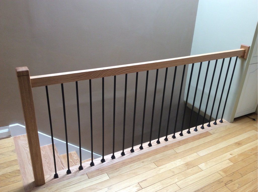 A staircase with a wooden railing and black metal bars