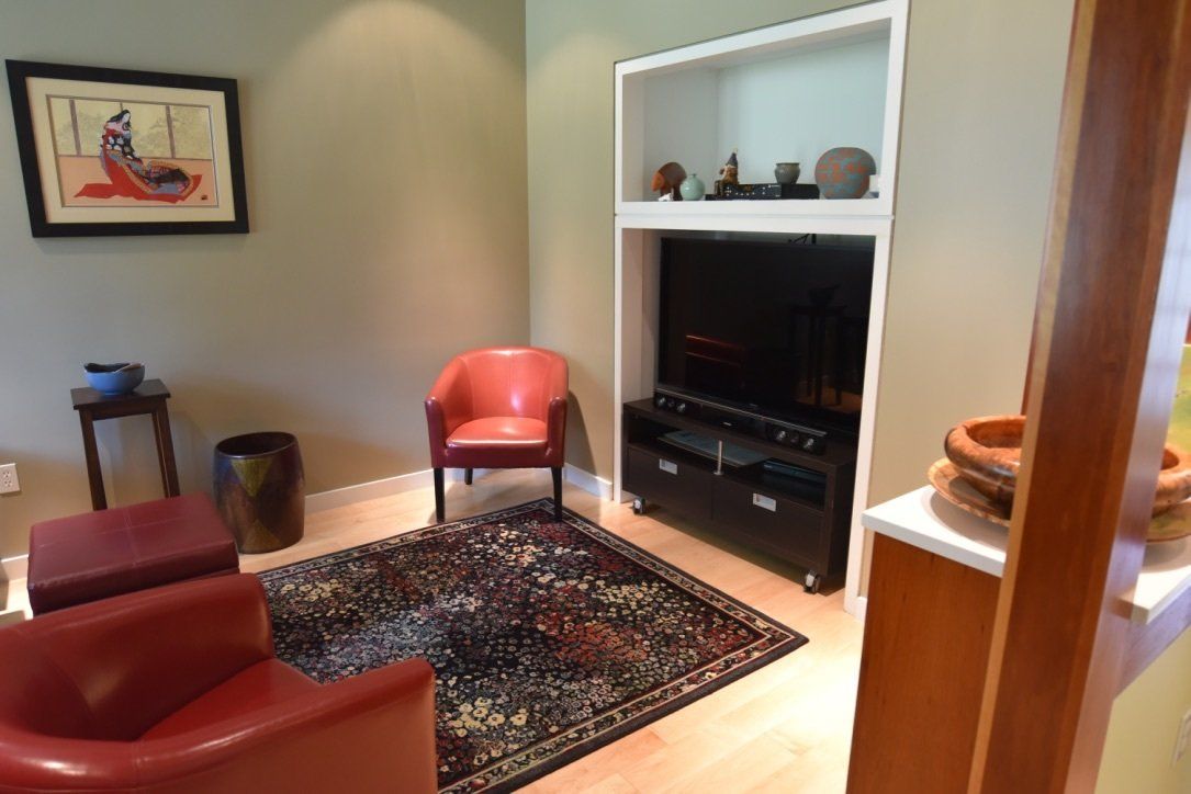 A living room with two red chairs and a flat screen tv