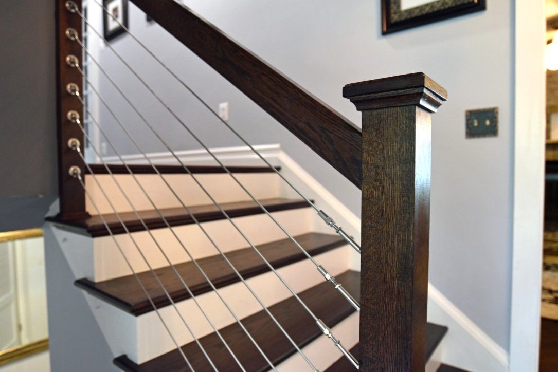 A staircase with a stainless steel railing and a wooden post