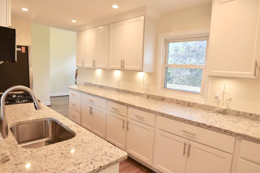 A kitchen with white cabinets and granite counter tops