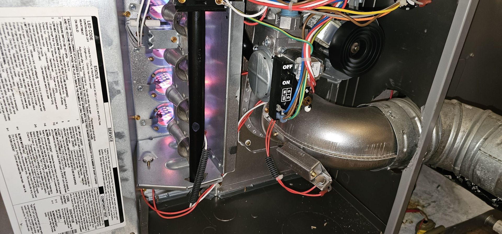 The inside of a heating system with a lot of wires coming out of it.