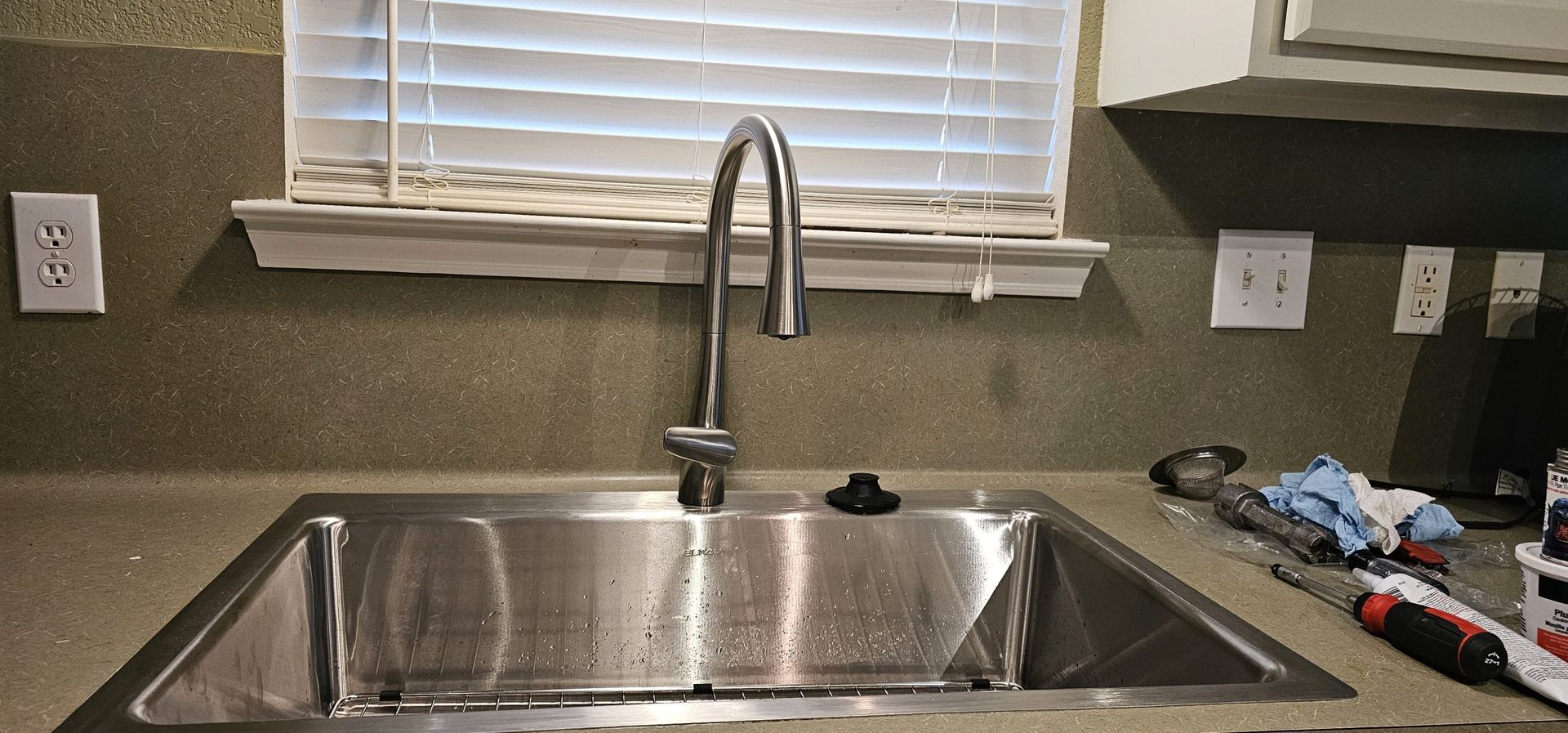 A kitchen sink with a faucet and a window in the background