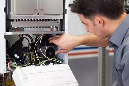 A man is working on a boiler in a factory.