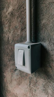 A person is working on an electrical box with a screwdriver.