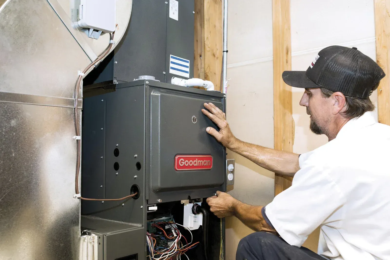 A man is working on an air conditioner in a basement.