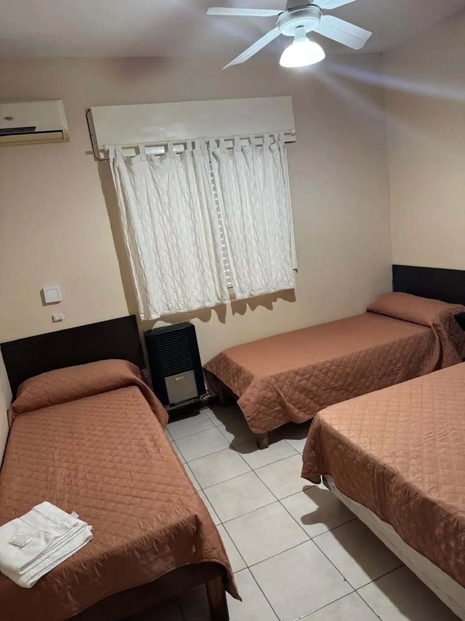 Dos camas individuales con colchas grises estampadas en una habitación con una mesita de noche central