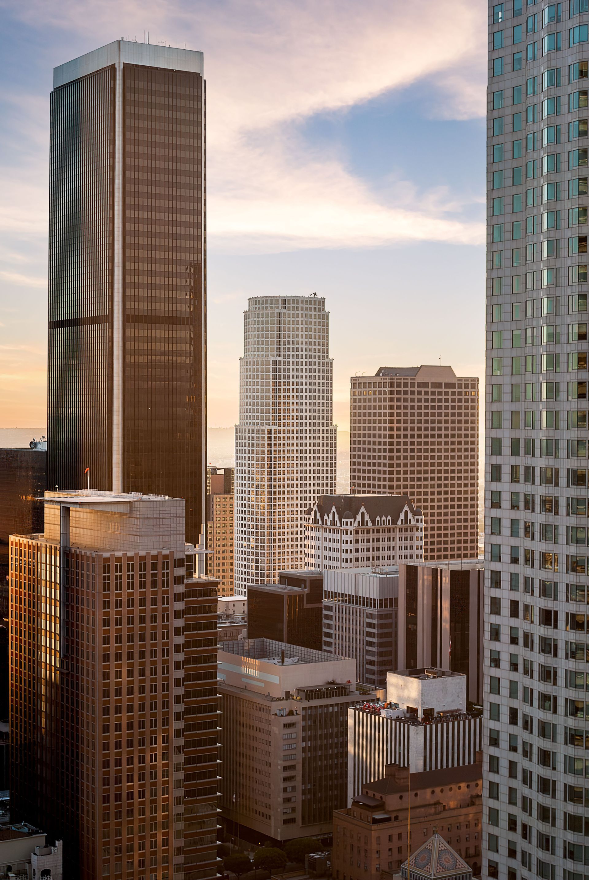 City skyline with tall skyscrapers, some brown and some white, under a dusky sky.