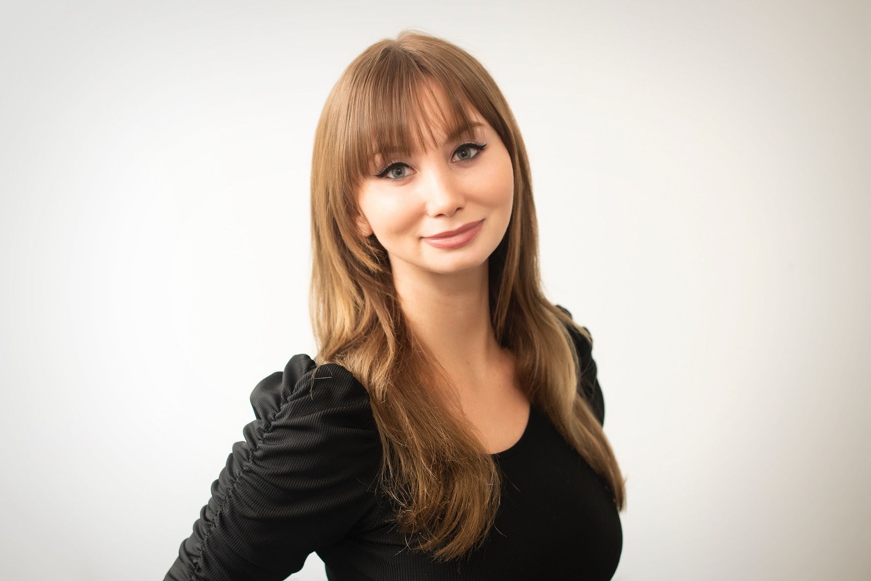 The woman is wearing a black shirt and smiling for the camera.