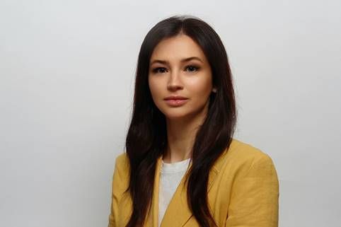 Die Frau trägt eine gelbe Jacke und ein weißes Hemd.