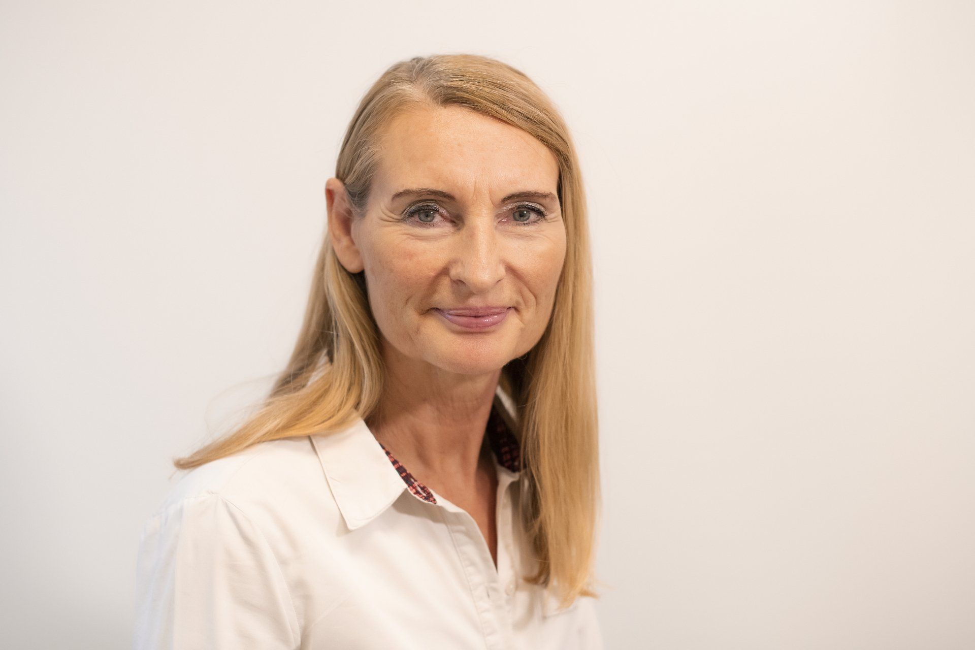 A woman in a white shirt is smiling for the camera.