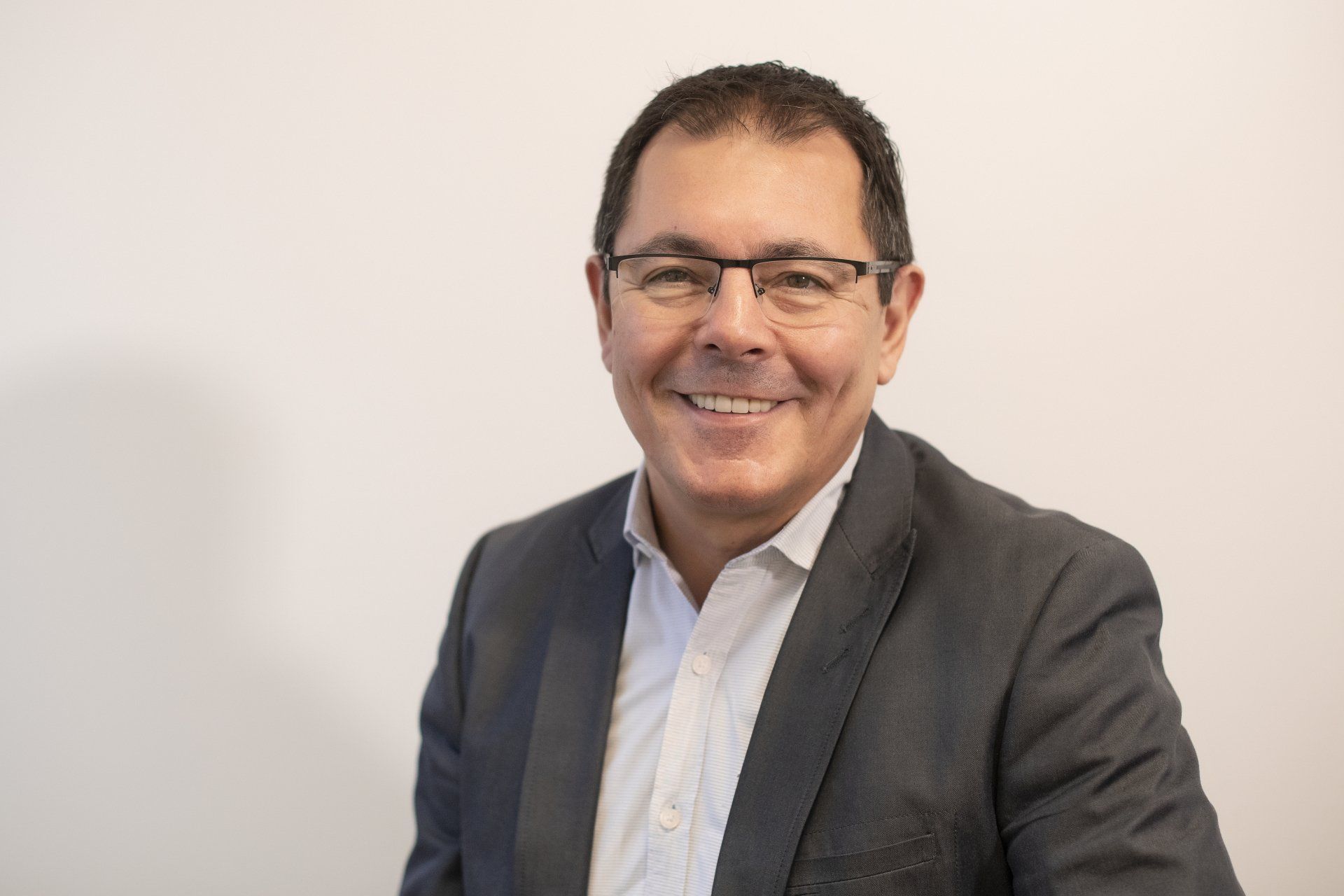 A man in a suit and glasses is smiling for the camera.