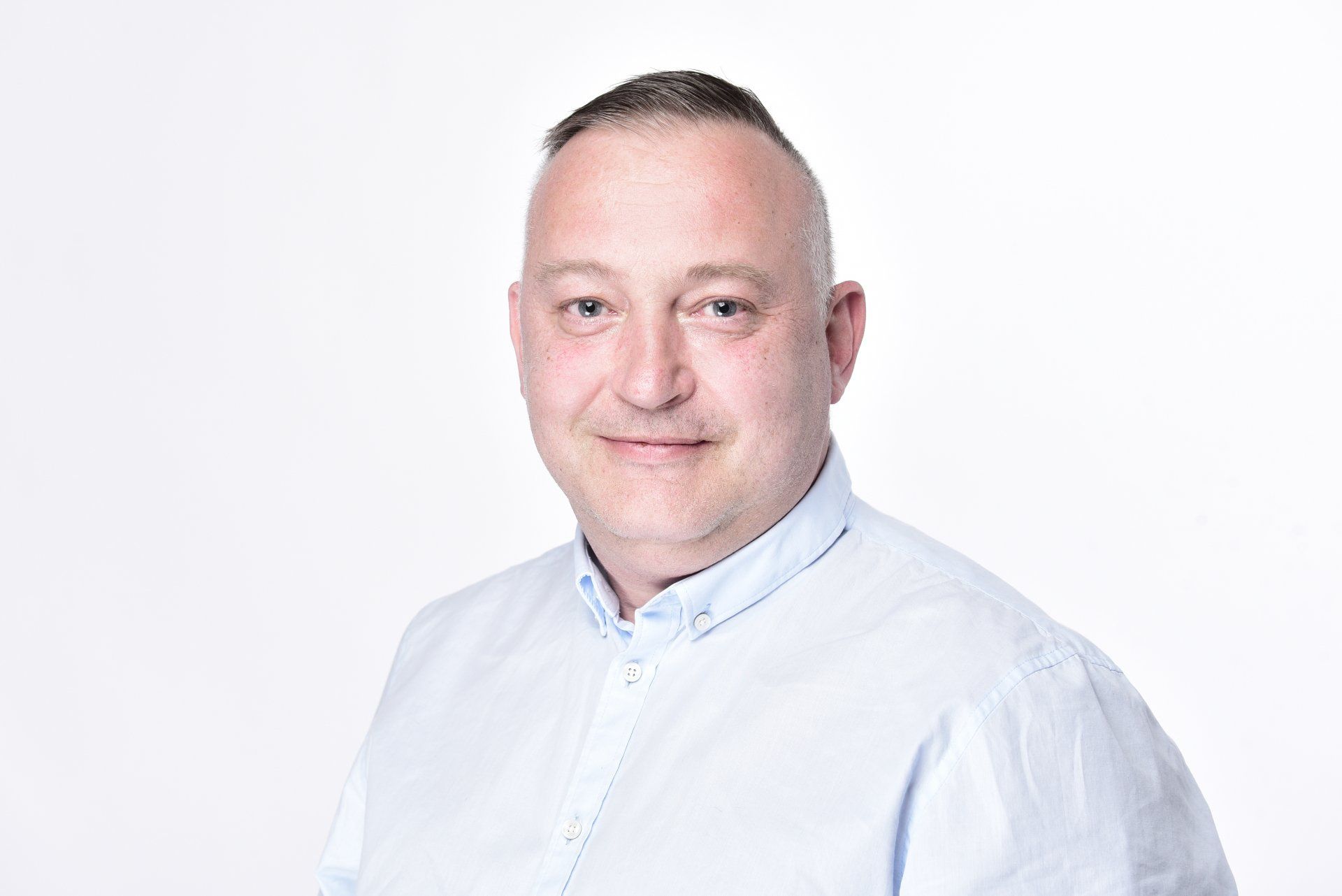 A man in a blue shirt is smiling for the camera.