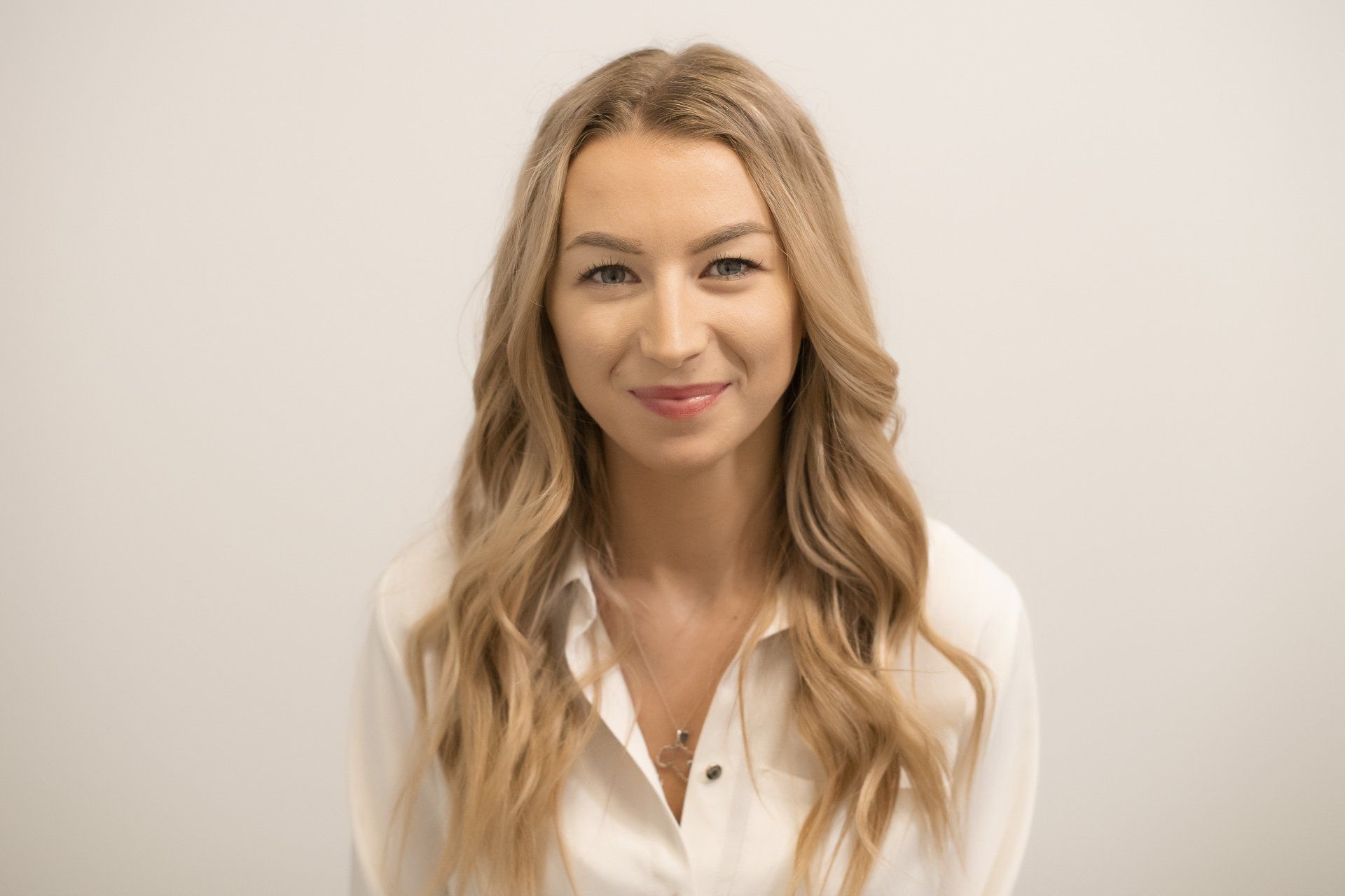The woman is wearing a white shirt and smiling for the camera.