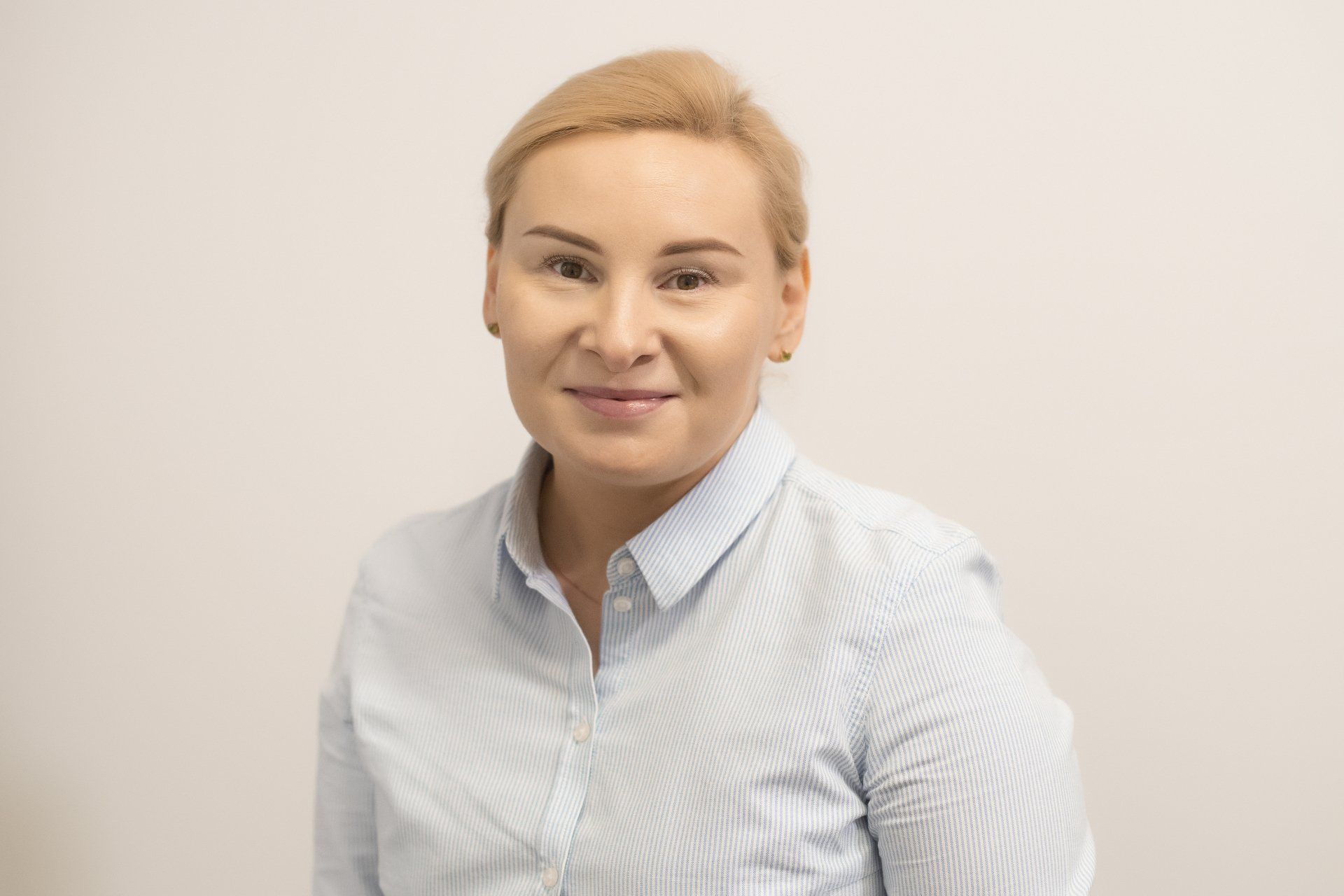 A woman in a blue striped shirt is smiling for the camera.