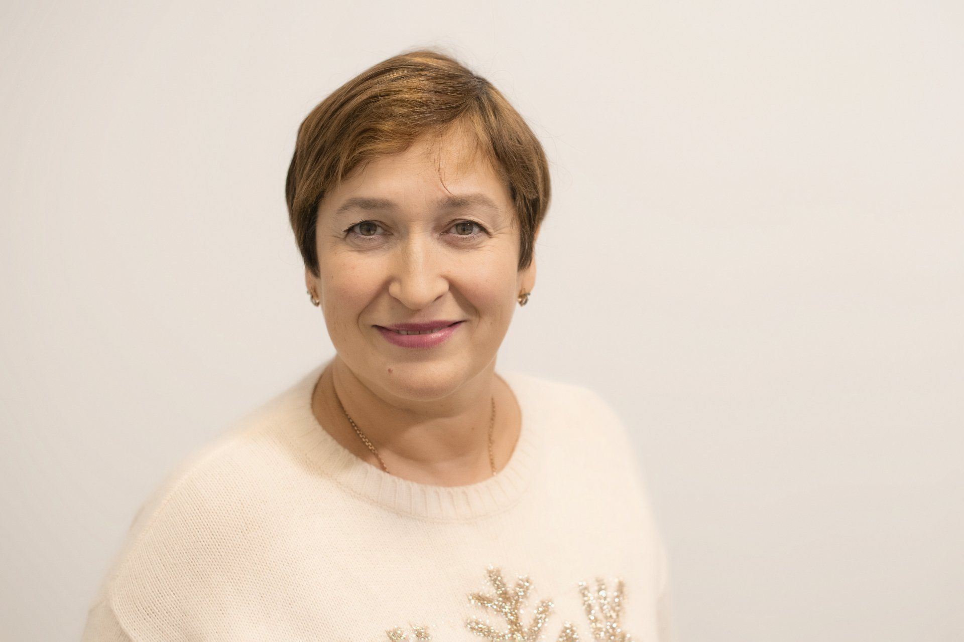 A woman in a white sweater is smiling for the camera.