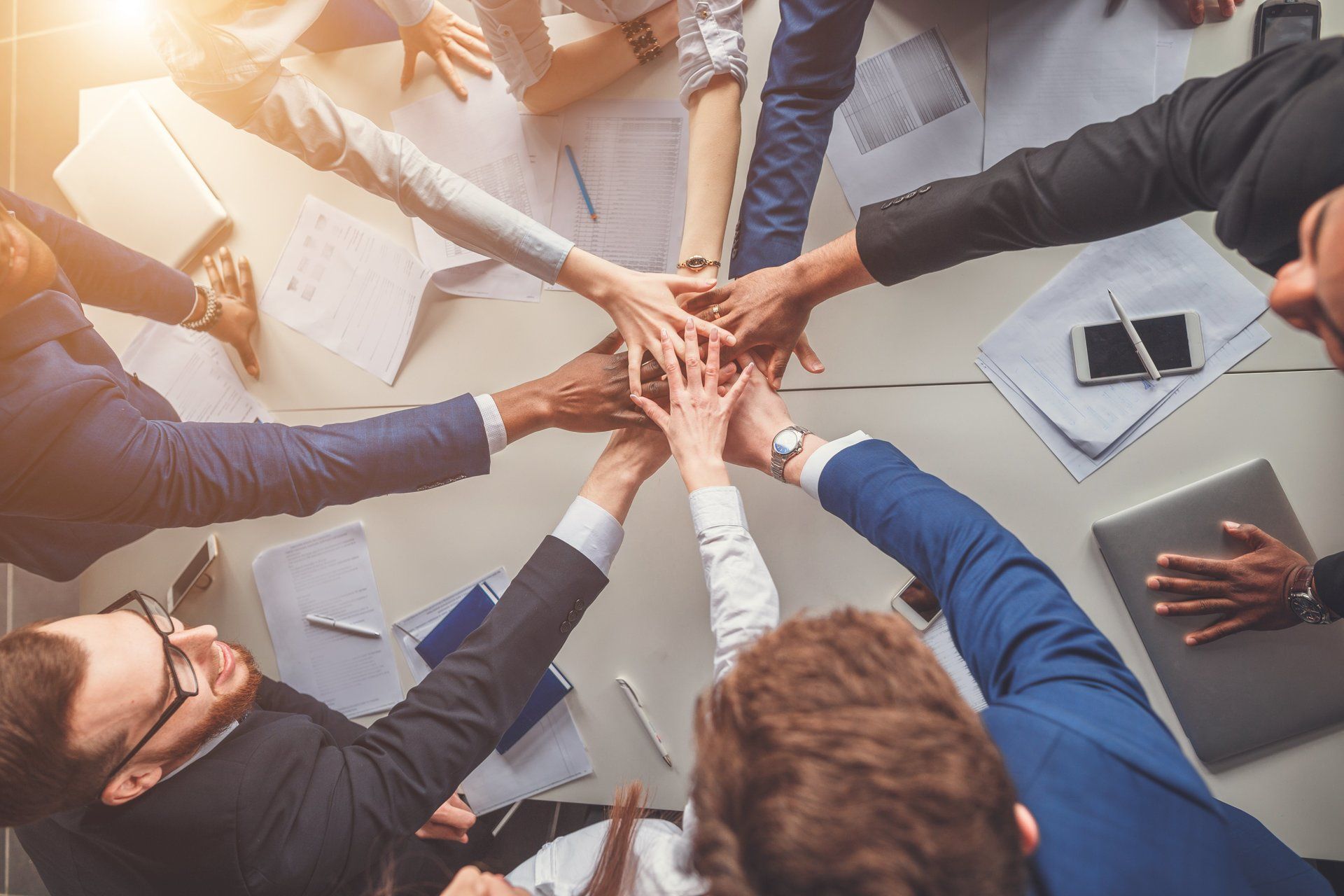 A group of people are putting their hands together in a circle.