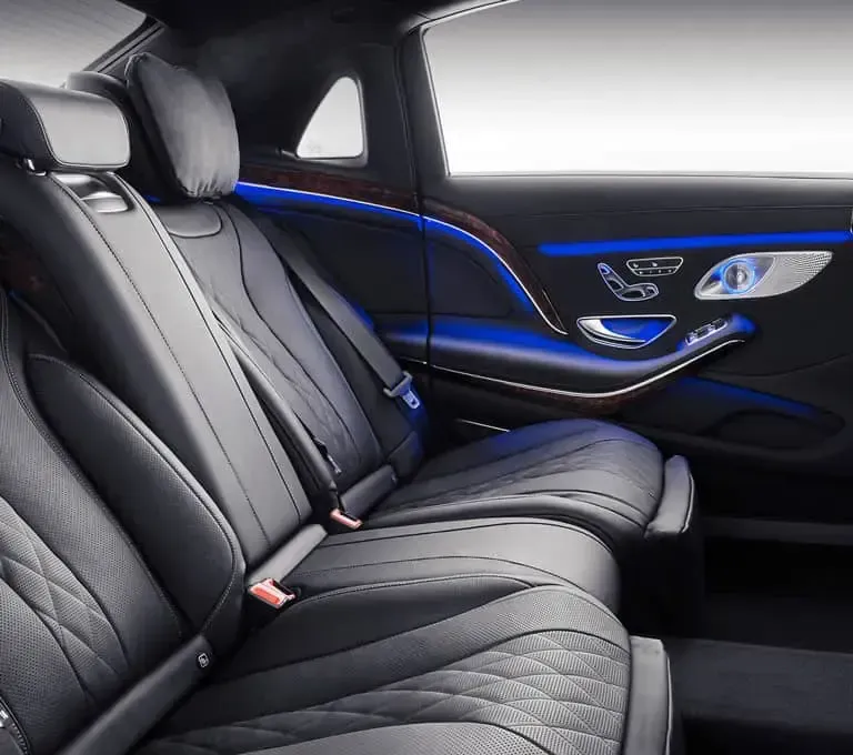 Black leather backseat of a luxury car with blue ambient lighting.