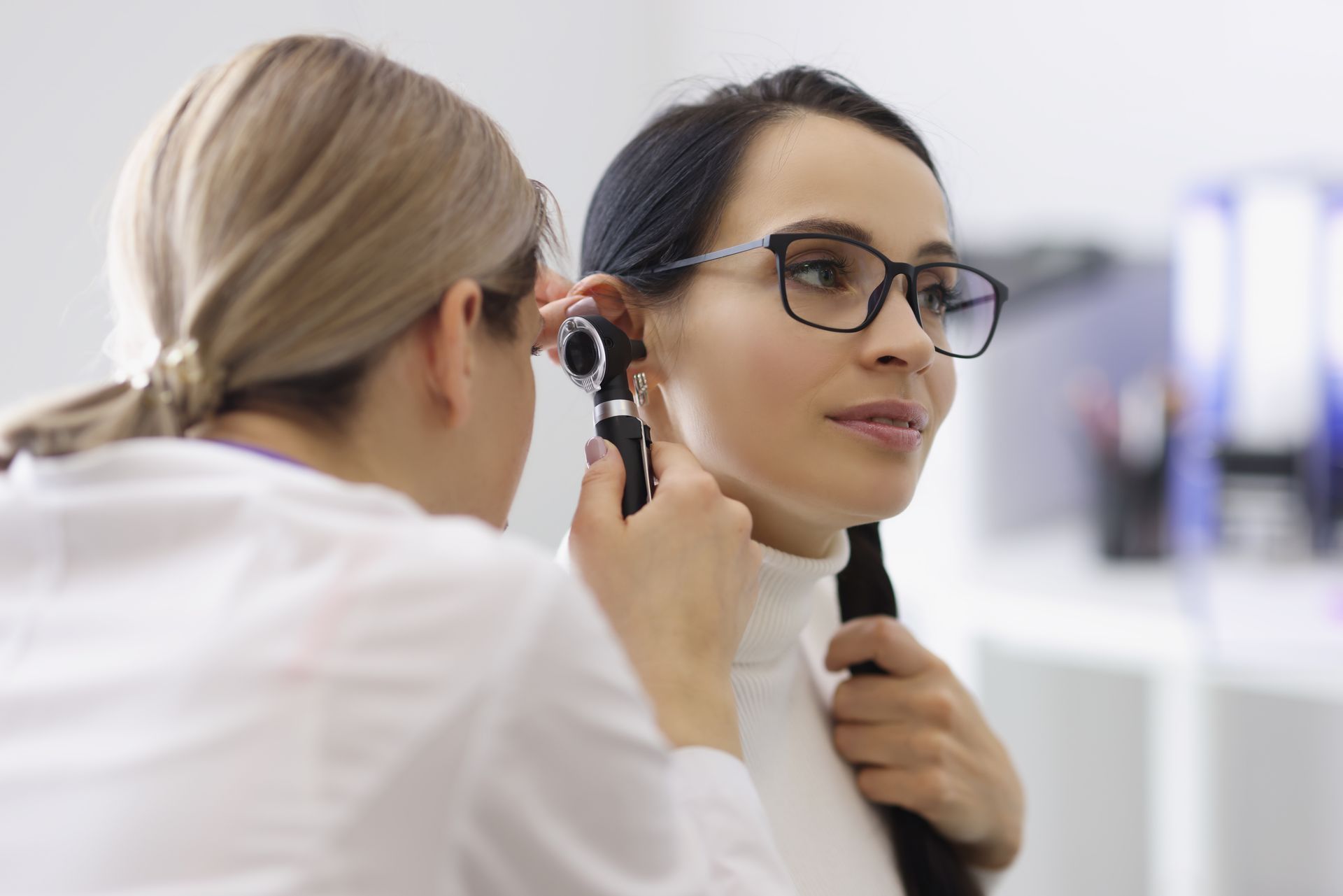 A doctor is examining a woman 's ear with an otoscope.
