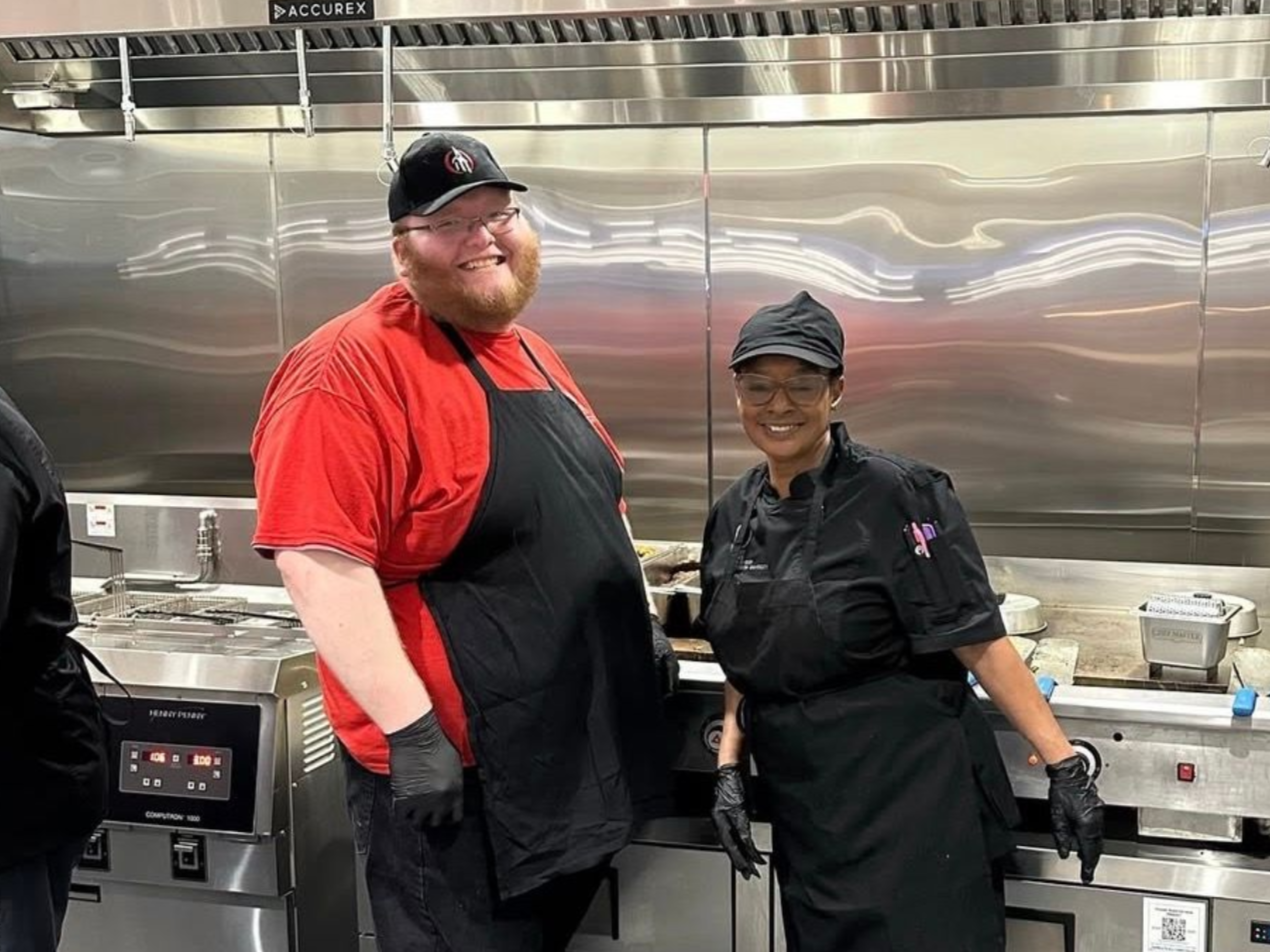 A man in a chef 's hat is posing for a picture with two other chefs